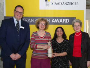 Drei Frauen und ein Mann. Zwei der Frauen halten die Trophäe in der Hand.