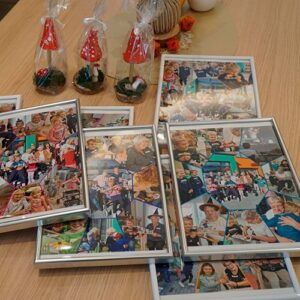 Eine Sammlung gerahmter Collagen mit Fotos von gemeinsamen Aktivitäten zwischen älteren Menschen und Kindern liegt auf einem Tisch, dekoriert mit kleinen Pilzen.