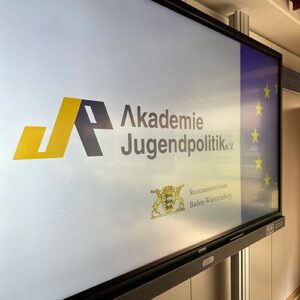 Eine Präsentation auf einem Bildschirm mit dem Logo der "Akademie Jugendpolitik e.V.", dem Wappen von Baden-Württemberg und der Europaflagge.