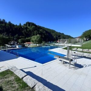 Modernisiertes Freibad in Nordrach mit Schwimmbecken, Sprungturm und Blick auf die umliegende Landschaft.