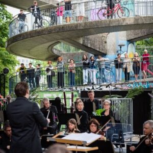 Orchester der Bodensee Philharmonie spielt unter freiem Himmel vor Publikum auf einer Brücke