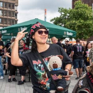 Konzertbesucherin mit Bandshirt und Stofftier feiert auf einem Fan-Event