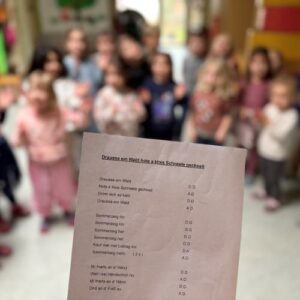 Kindergruppe im Kindergarten mit Liedtext auf Schwäbisch im Vordergrund