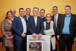 Gruppe präsentiert Projekt „Kostenlose musikalische Ausbildung für alle Kinder“ mit Plakat beim Staatsanzeiger Award 2025.