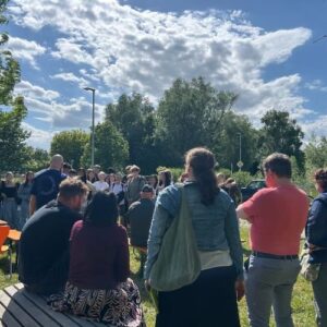 Gruppe von Menschen bei einer Versammlung im Freien unter blauem Himmel