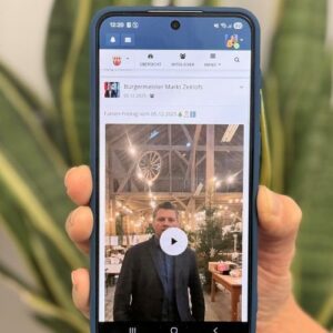 Bürgermeister präsentiert ein Video-Update in der PocketDorf-App auf einem Smartphone