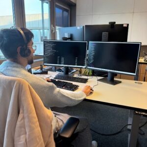 Mitarbeiter arbeitet an zwei Monitoren mit Programmcode im Büro