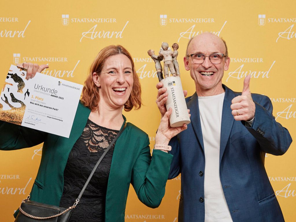 Zwei Personen präsentieren Urkunde und Trophäe des Staatsanzeiger Awards 2025 und freuen sich über den ersten Platz für das Projekt der Stadt Pforzheim.