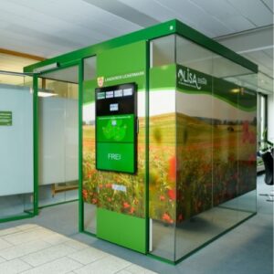 Raum-in-Raum-System LISA im Innenbereich eines Verwaltungsgebäudes, grüner Beratungsraum mit Display und Zugangstür